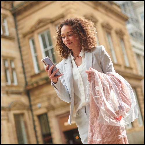 A picture of a woman in business attire with her dry cleaning 